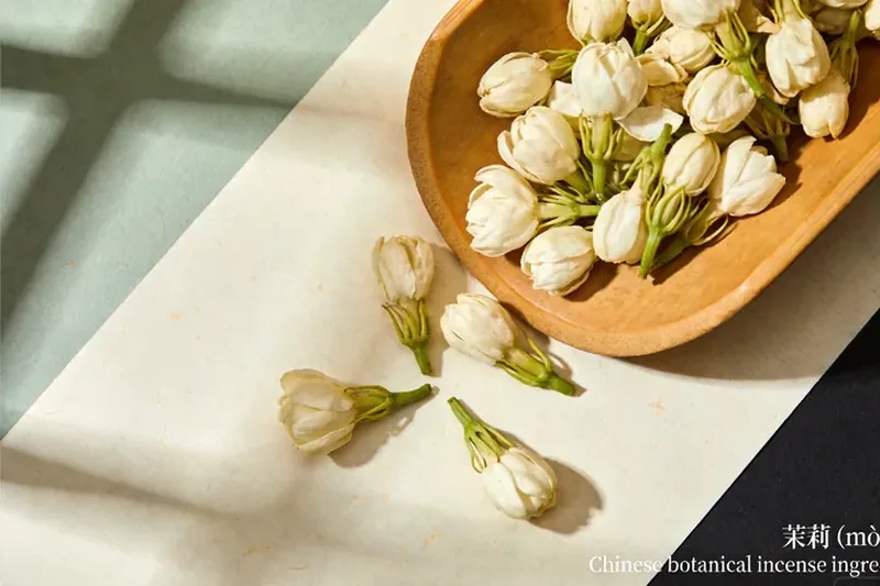 Dried white jasmine blossoms in a small ceramic dish.